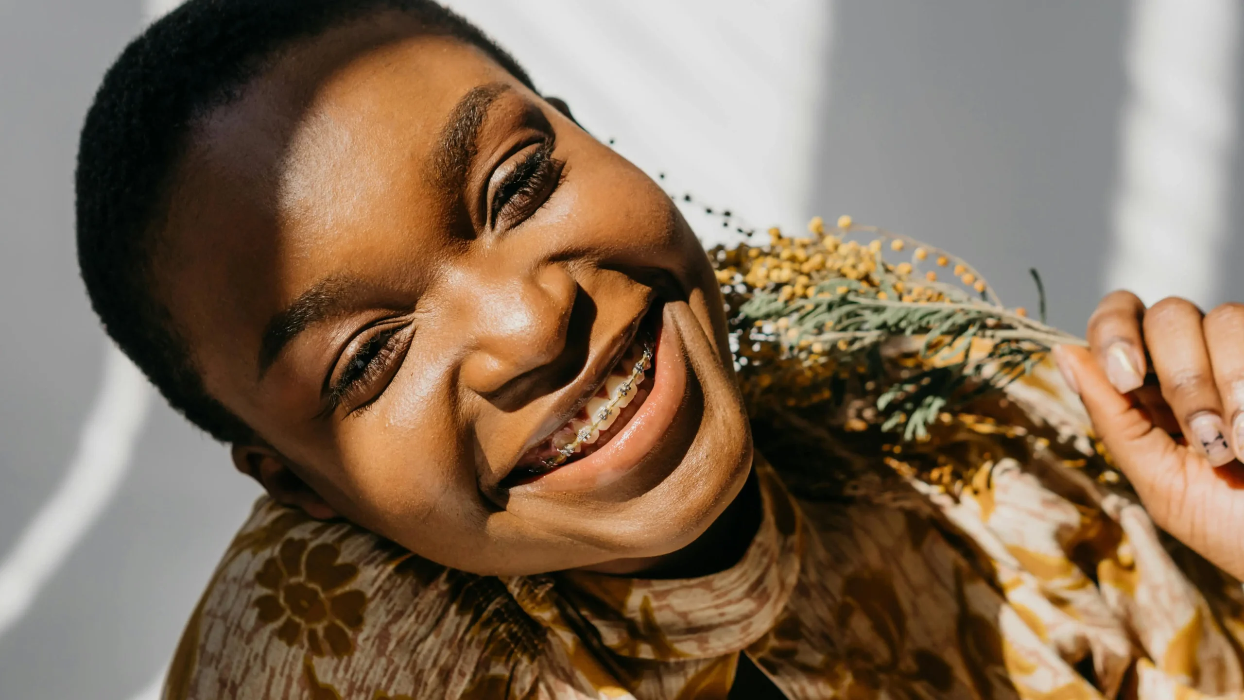 Woman with braces smiling, questioning are braces faster than Invisalign?