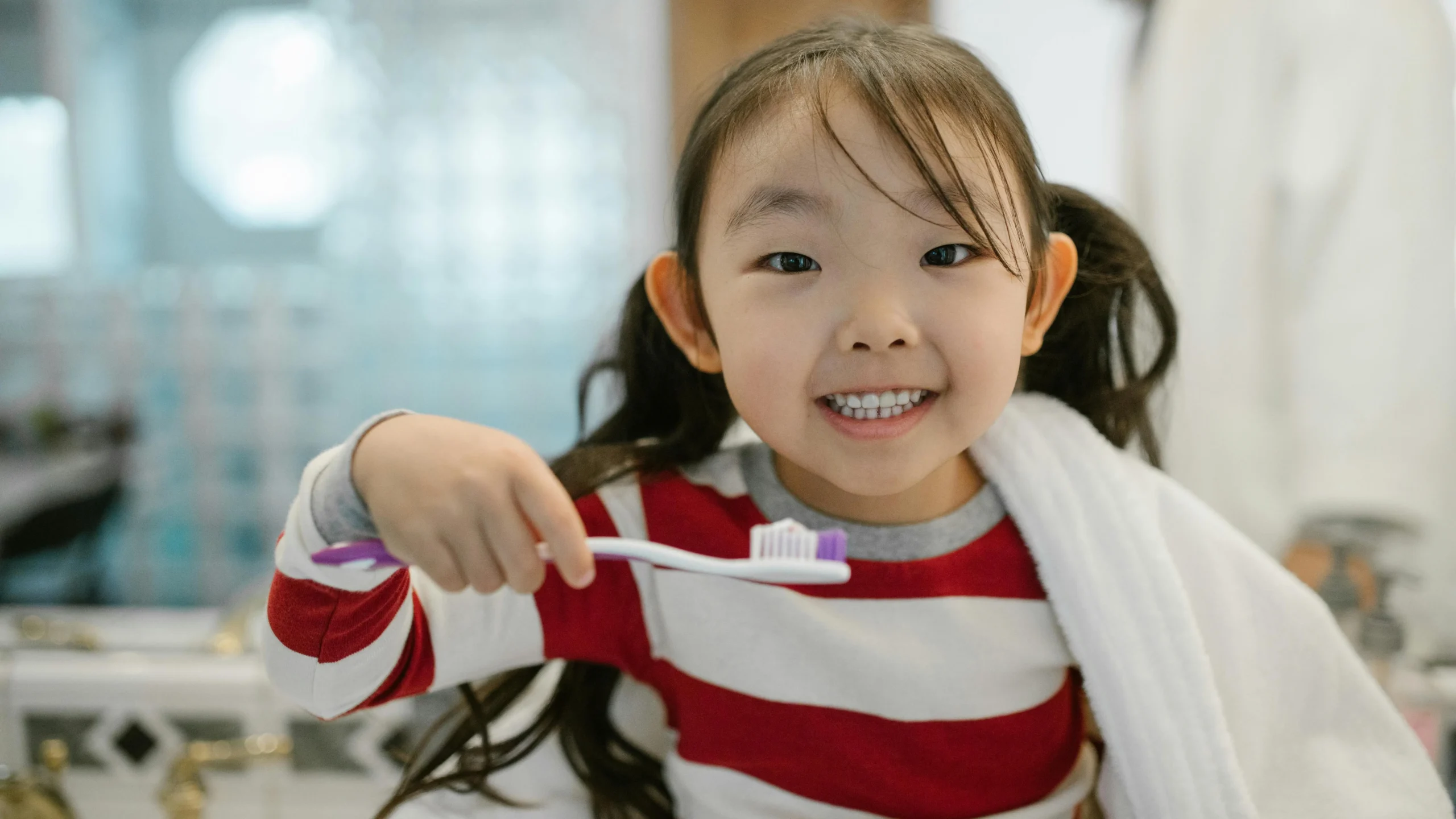 Cheerful child brushing teeth with help from child dental care specialist