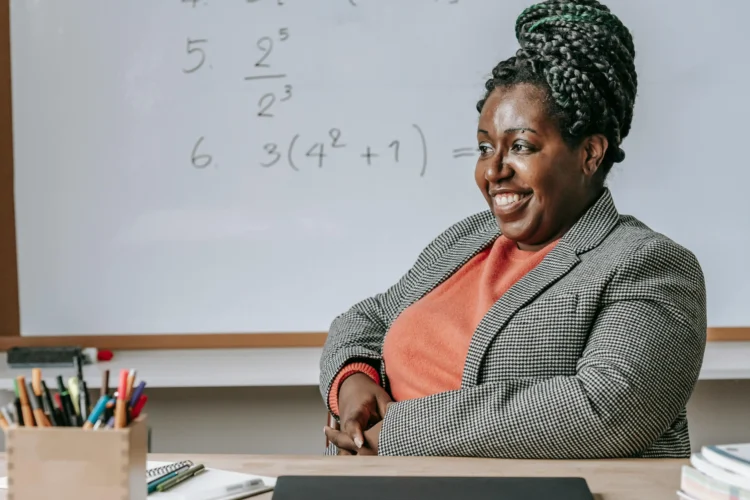 African American woman with a bright smile in classroom, illustrating cosmetic dentistry for adults.