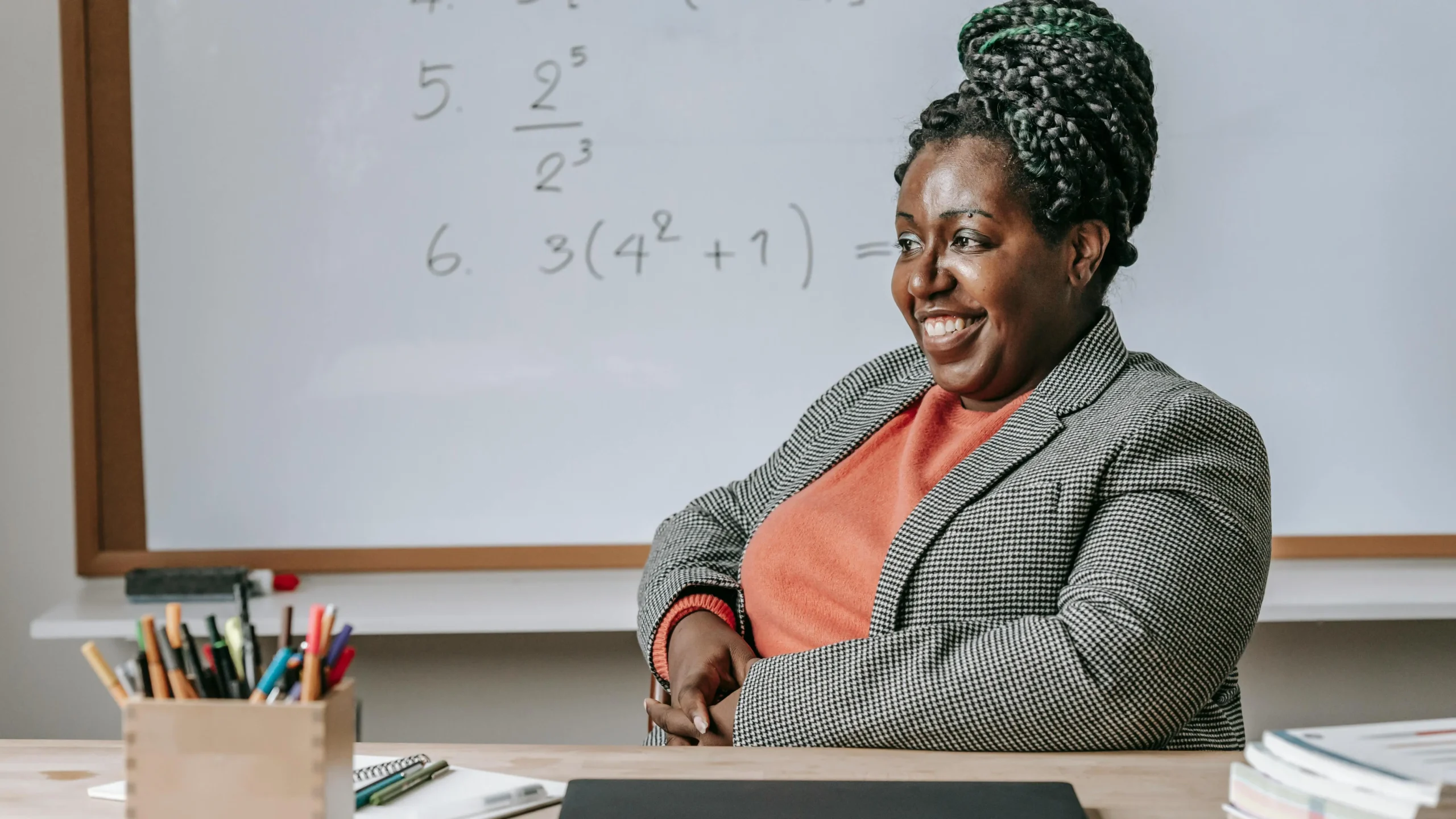 African American woman with a bright smile in classroom, illustrating cosmetic dentistry for adults.