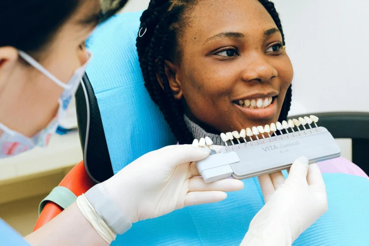 Cheerful woman in dental chair examining dental implant in Cookstown office.