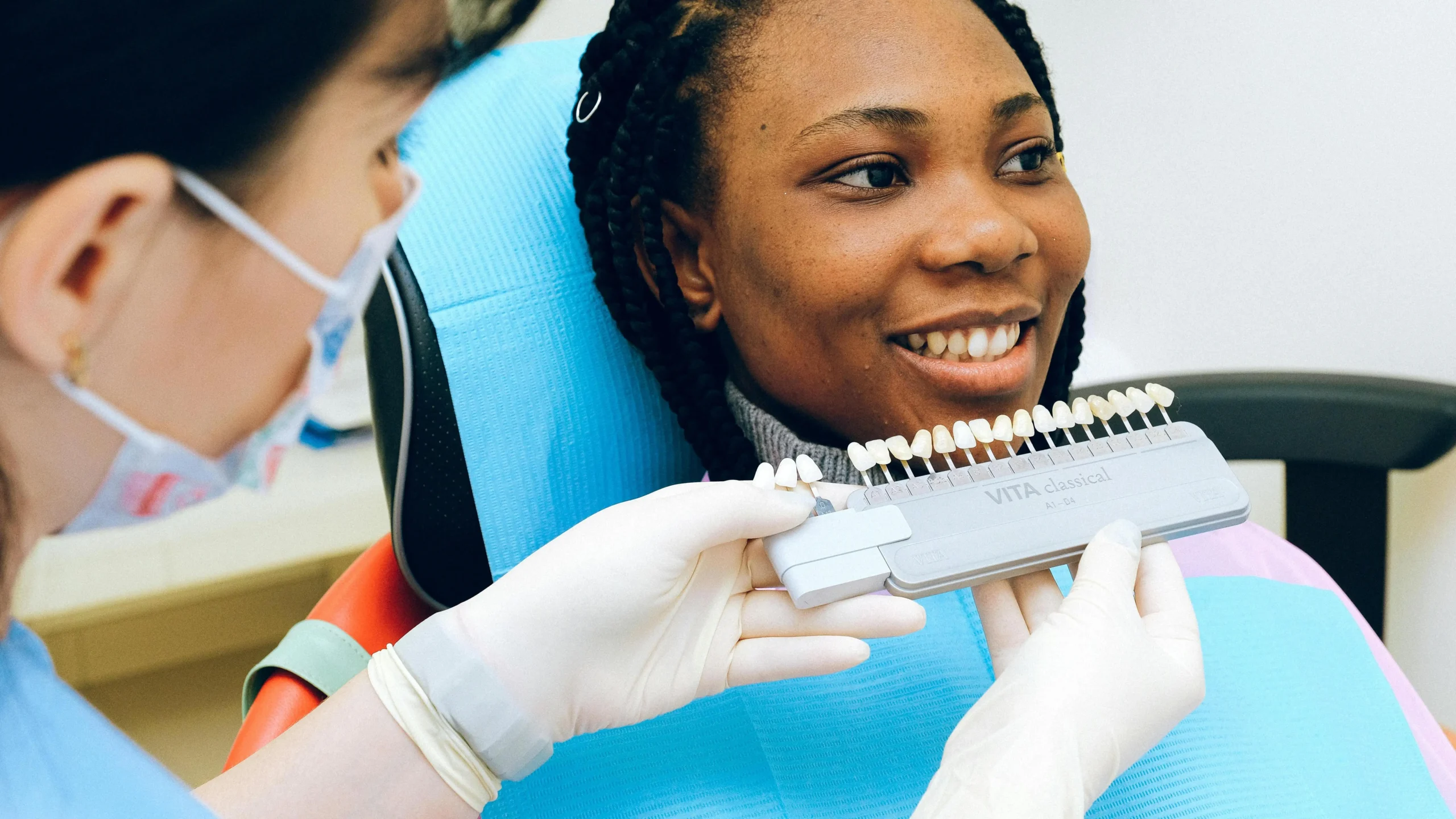 Cheerful woman in dental chair examining dental implant in Cookstown office.