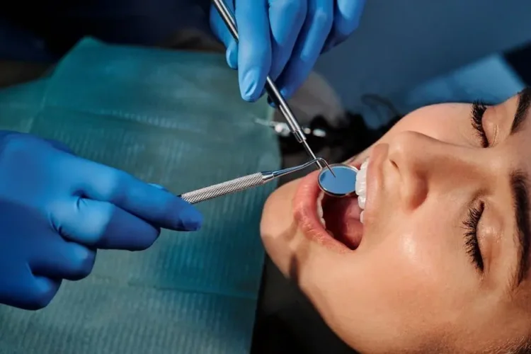 Dentist examining a woman's teeth to discuss implant dentistry cost