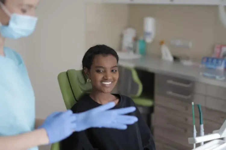 Smiling ethnic female patient with 24-hour emergency dentist in modern clinic