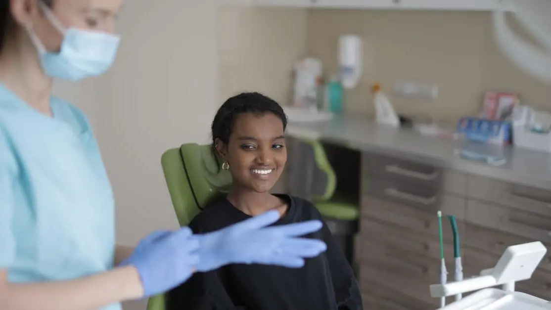 Smiling ethnic female patient with 24-hour emergency dentist in modern clinic