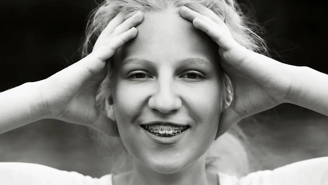 Smiling woman with braces, highlighting why adults get braces for improved dental health.