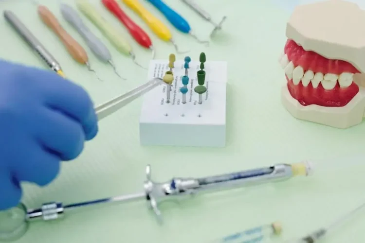 Orthodontist using tweezers with dental tools like periodontal scalers and a cast jaw at a medical table