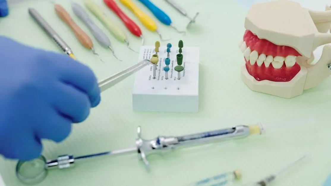 Orthodontist using tweezers with dental tools like periodontal scalers and a cast jaw at a medical table