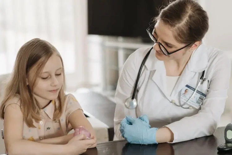 Smiling pediatric dentist sitting with young girl by a table, embodying the best pediatric dentists.