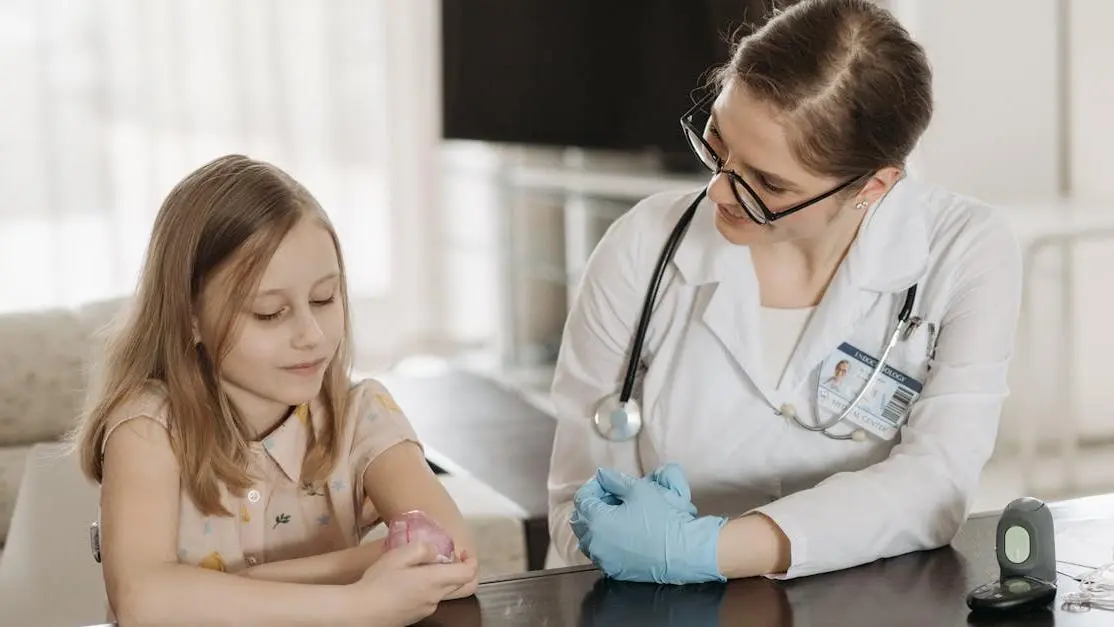 Smiling pediatric dentist sitting with young girl by a table, embodying the best pediatric dentists.