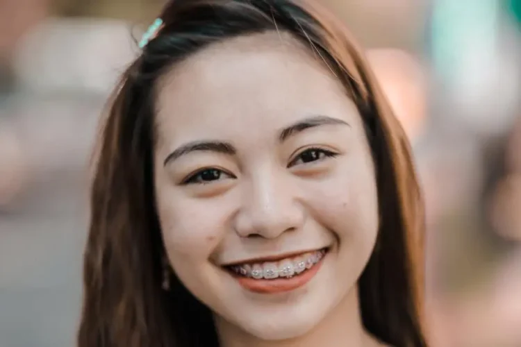 Smiling woman with braces practicing oral hygiene