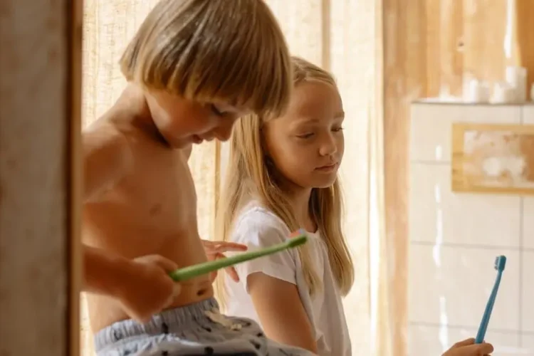 Siblings holding toothbrushes, promoting children's oral health tips.