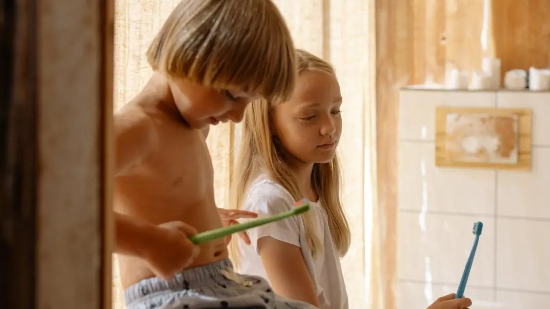 Siblings holding toothbrushes, promoting children's oral health tips.