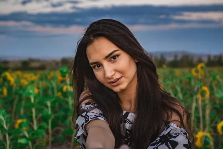 Woman taking selfie in sunflower field showcasing composite veneers