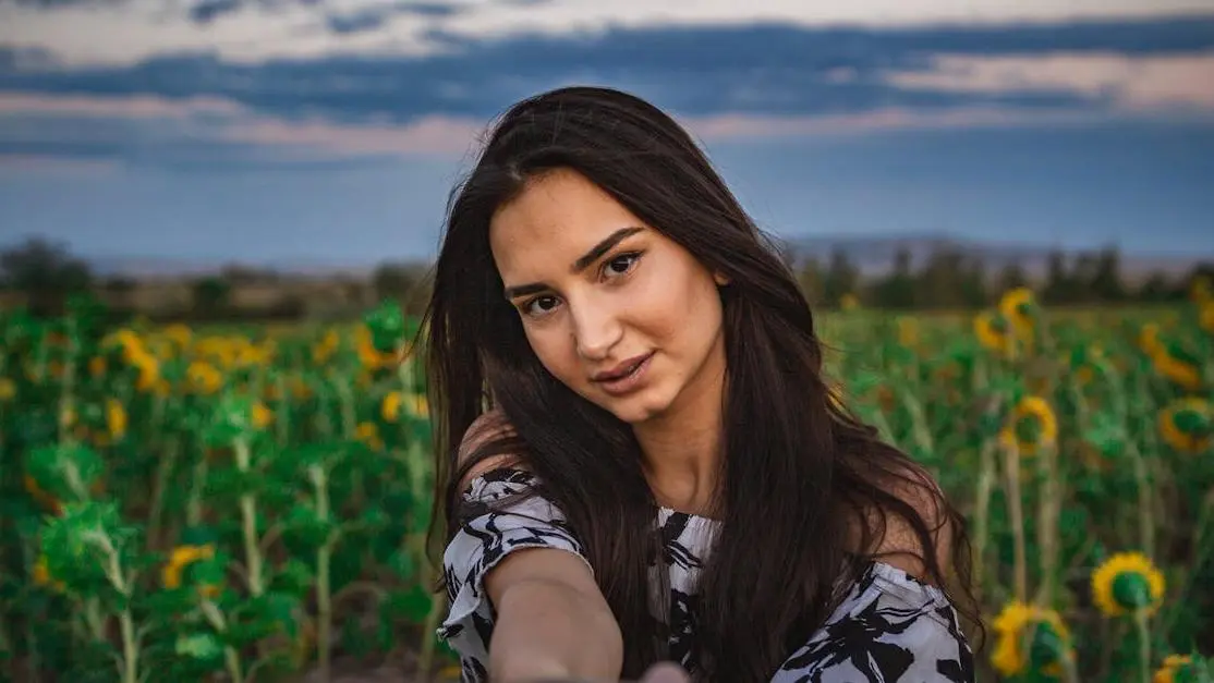 Woman taking selfie in sunflower field showcasing composite veneers