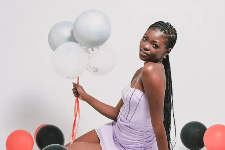 African woman smiling with balloons showcasing her cosmetic dental veneers.