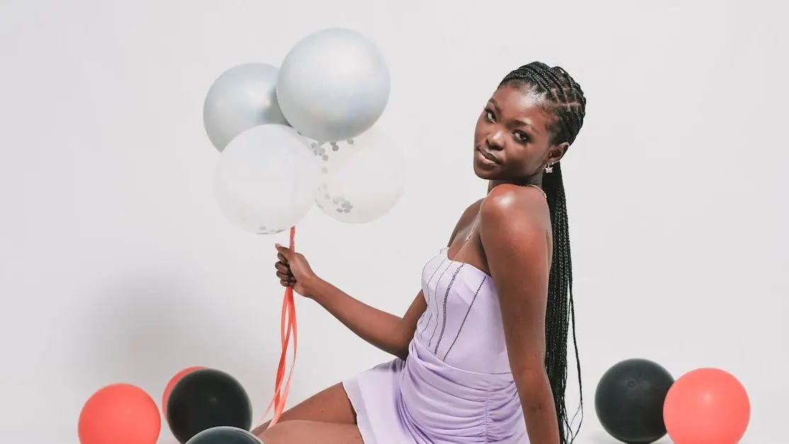 African woman smiling with balloons showcasing her cosmetic dental veneers.