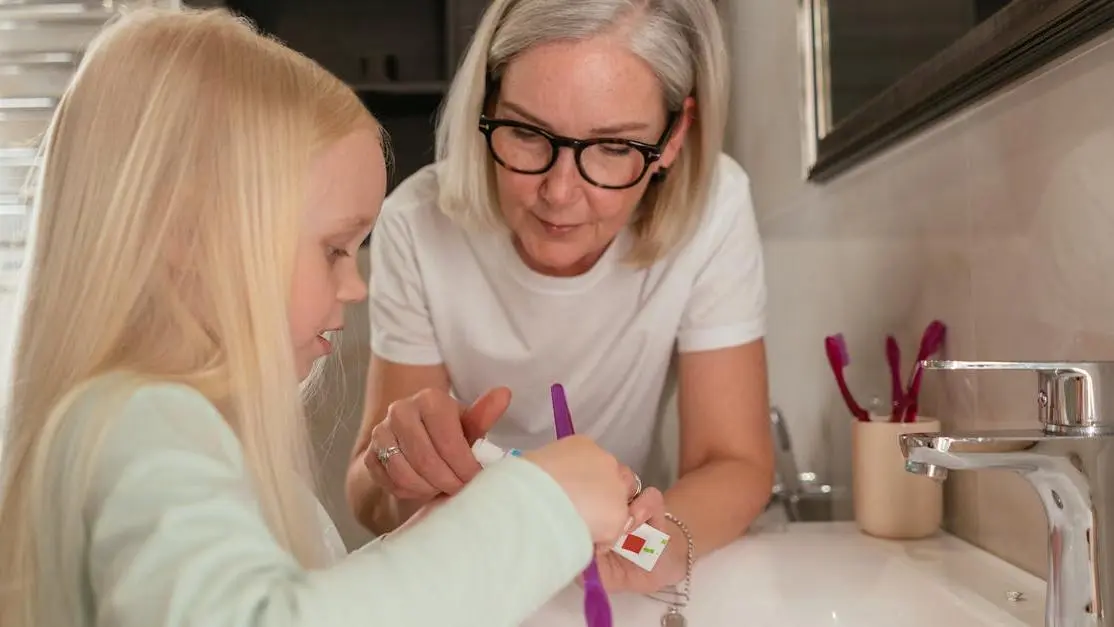 Grandmother guiding granddaughter in brushing for dental care for seniors.