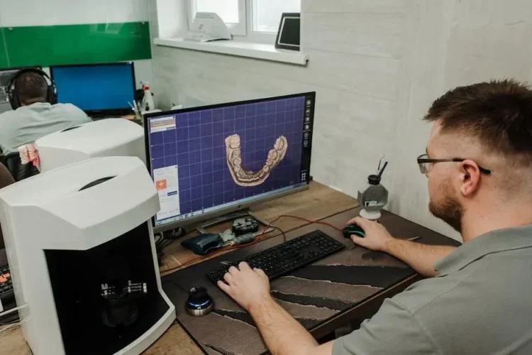 Male programmer creating 3D denture model in dental lab, showcasing digital impressions braces orthodontics.