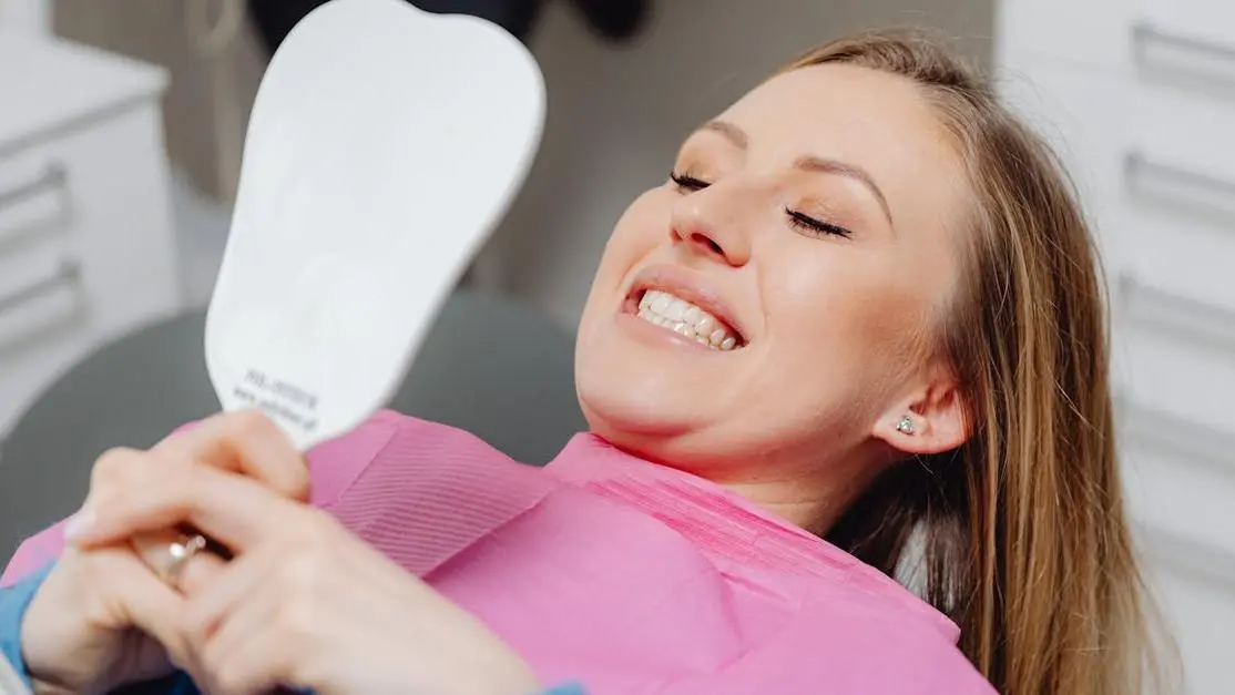 Thrilled patient admiring her smile with experienced cosmetic dentists' work reflected in the mirror.