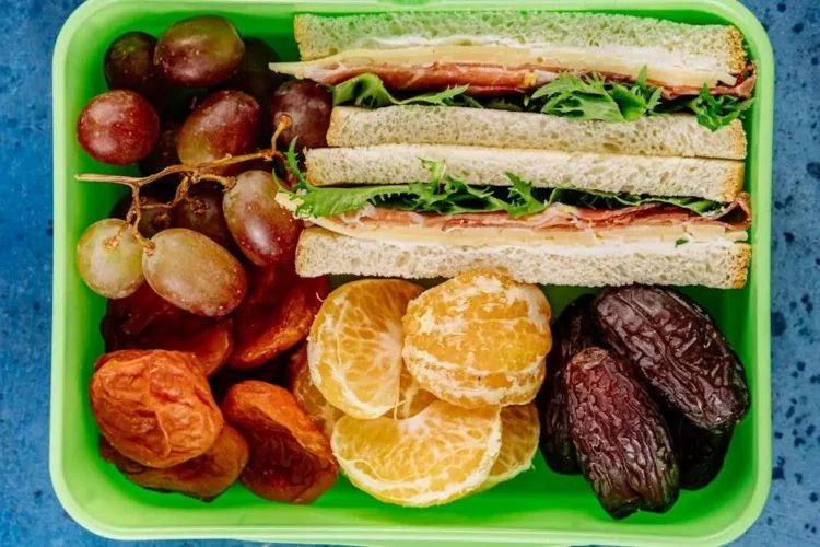 Healthy school lunch with sandwiches and fruit, promoting dental wellness.