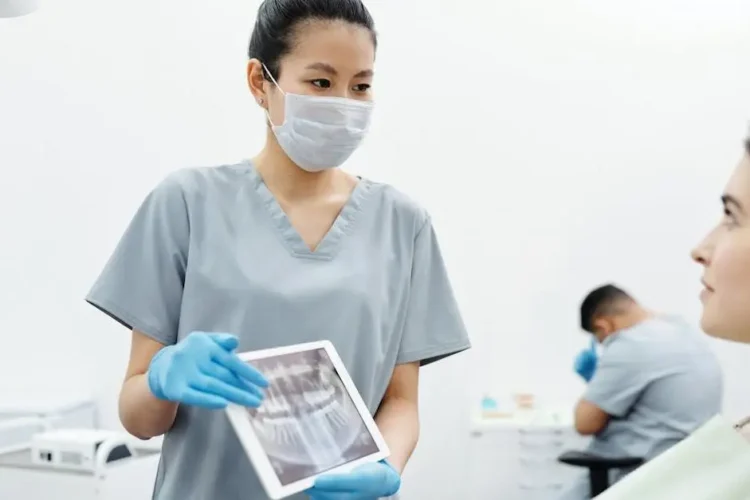 Dentist showing patient X-ray, highlighting implant dentistry advancements.