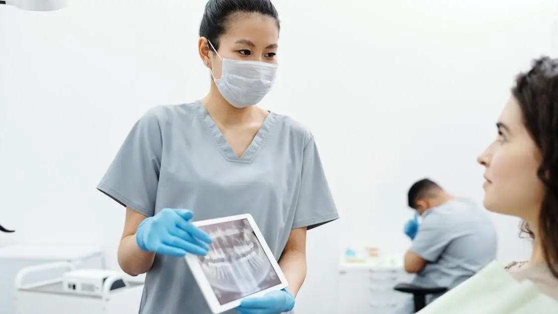 Dentist showing patient X-ray, highlighting implant dentistry advancements.