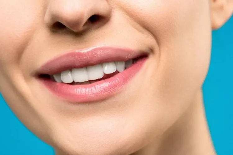 Smiling woman with pink lipstick showcasing implant supported dentures