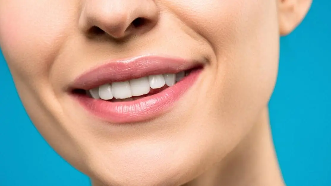 Smiling woman with pink lipstick showcasing implant supported dentures