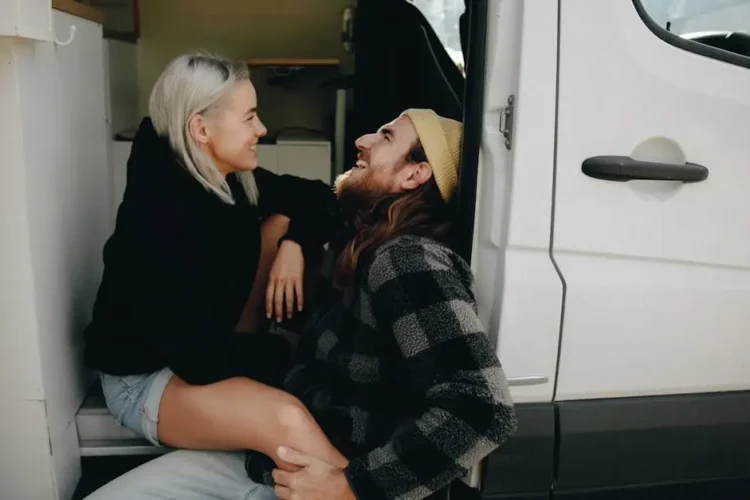 Happy couple sitting on a white van after visiting Invisalign dentists