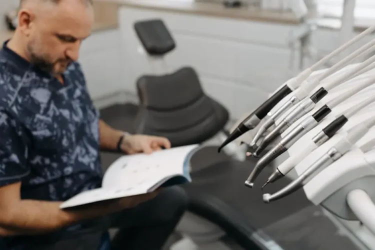 Man reading book by dental chair, illustrating IV sedation for dental anxiety relief.