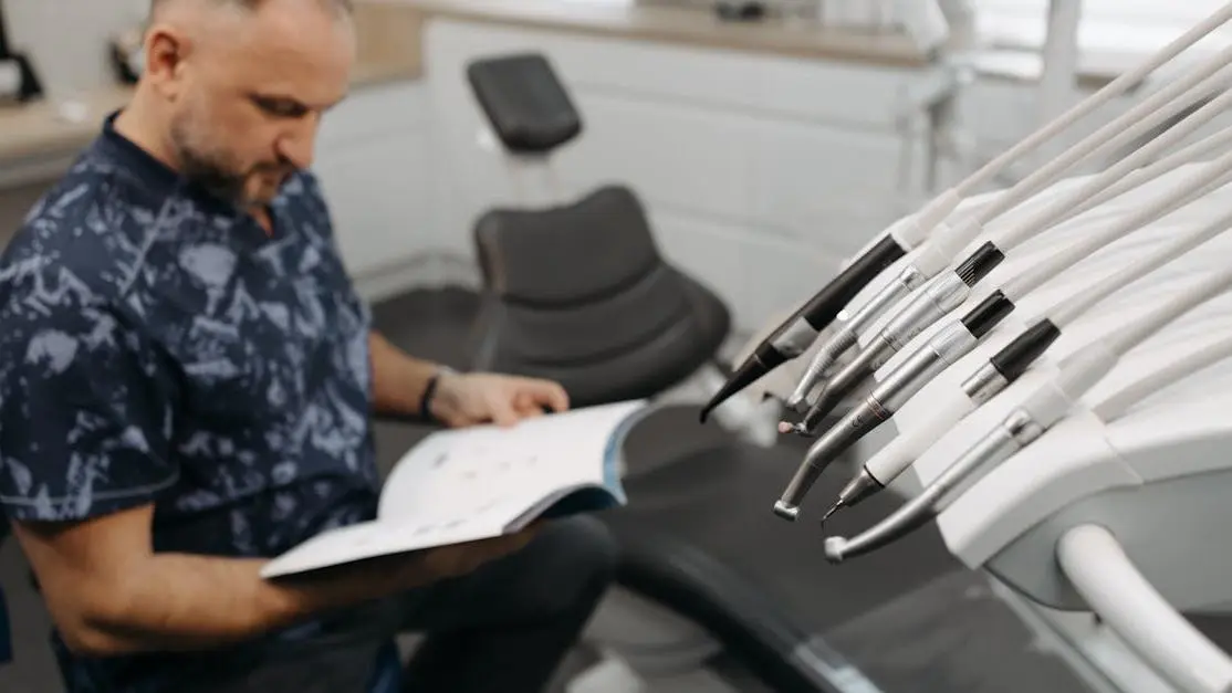 Man reading book by dental chair, illustrating IV sedation for dental anxiety relief.