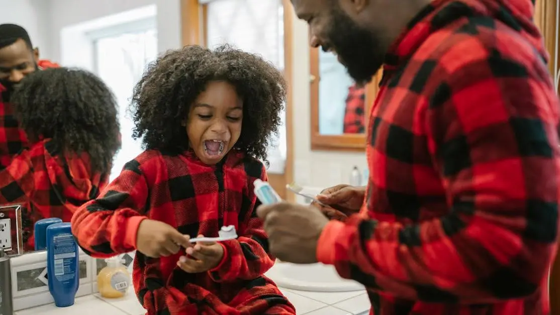 Father and daughter smiling brushing teeth, promoting kids dental care.