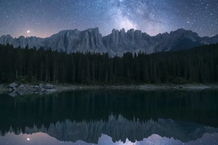 Night guard benefits: peaceful sleep under starry sky, pine trees and serene lake backdrop.