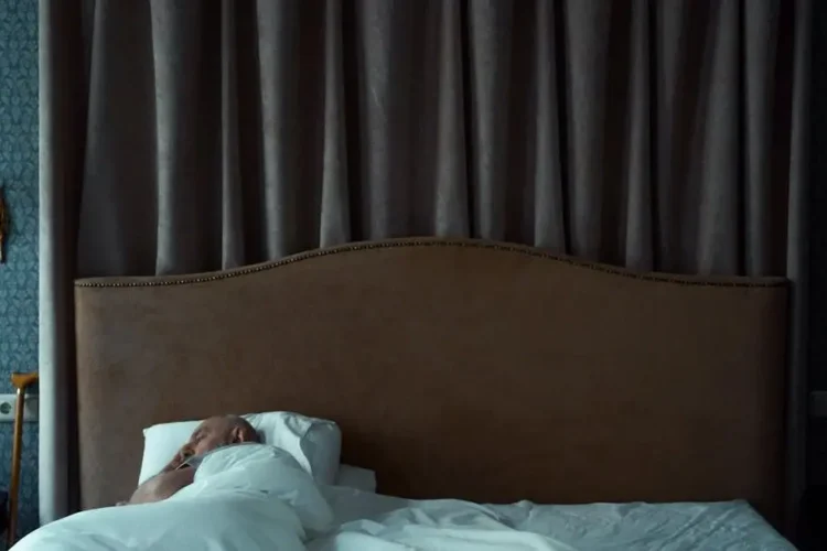 Man sleeping with a night guard for teeth grinding, under a white blanket.