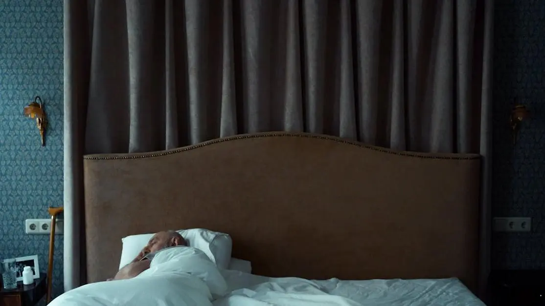 Man sleeping with a night guard for teeth grinding, under a white blanket.