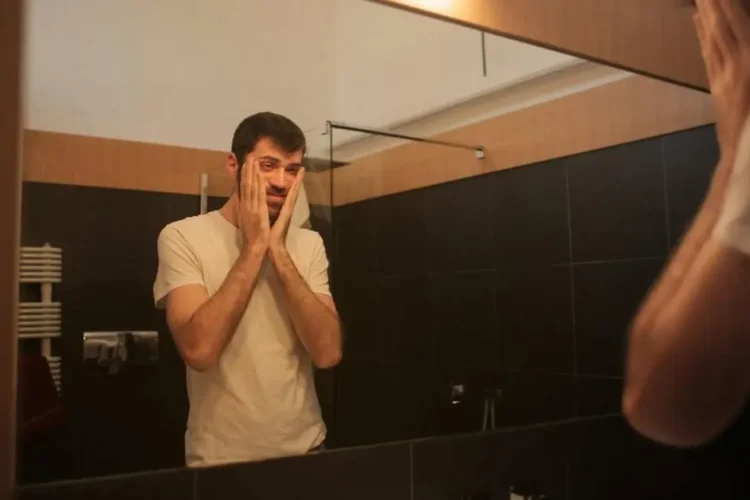 Man examining mouth in mirror for oral cancer signs