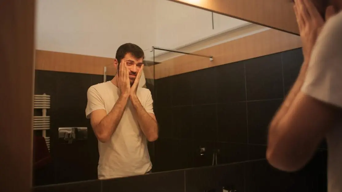 Man examining mouth in mirror for oral cancer signs