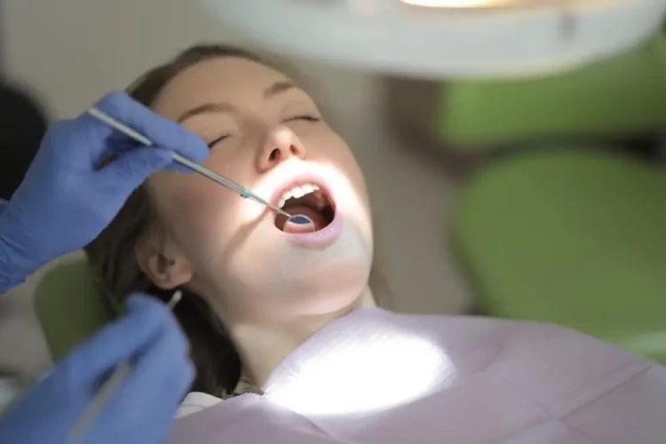 Dentist examining patient's teeth for oral cancer symptoms in clinic