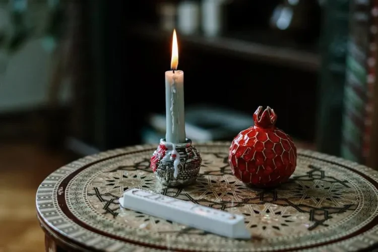 Festive table with candle and ceramic pomegranate; oral health tips tricks holiday season.