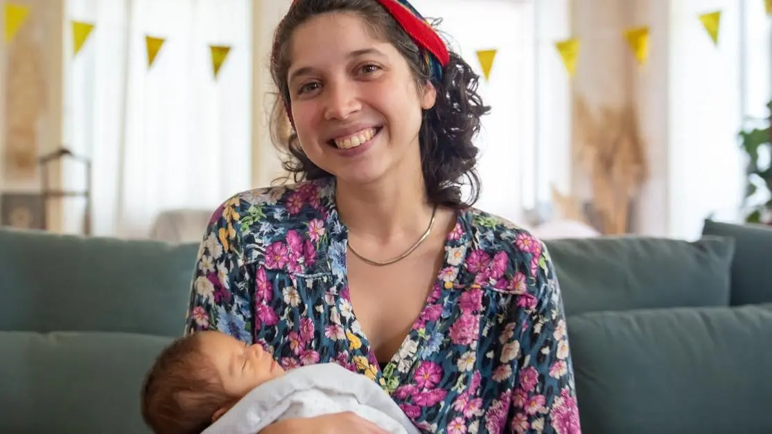 Smiling woman on couch, representing pain-free dental experience.