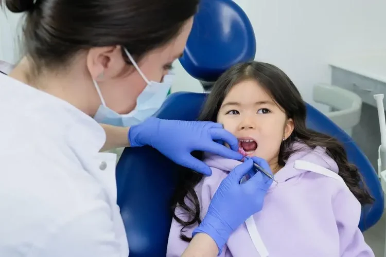 Dentist performing pediatric dentistry on a girl.