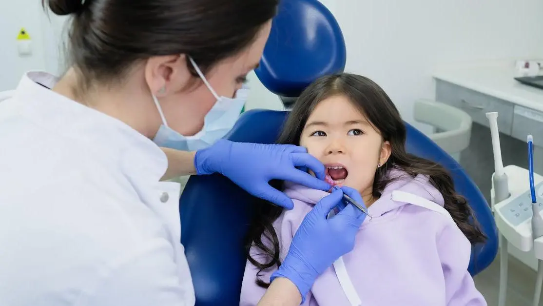 Dentist performing pediatric dentistry on a girl.