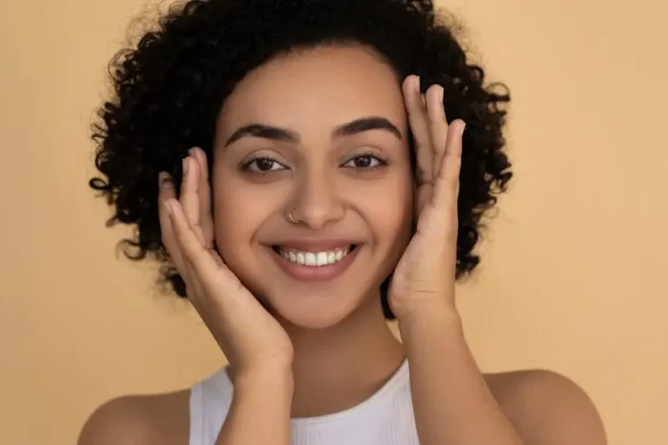 Smiling woman in white tank top demonstrating how to prevent and treat bad breath.