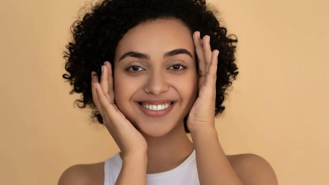 Smiling woman in white tank top demonstrating how to prevent and treat bad breath.