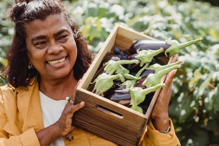 Middle-aged woman carrying fresh eggplants, symbolizing preventing orthodontic problems through healthy eating