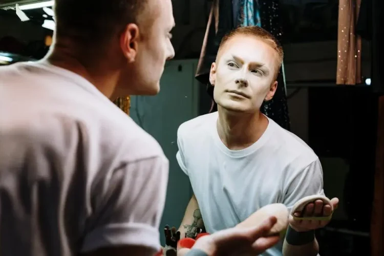 Drag queen applying makeup related to prosthodontics.