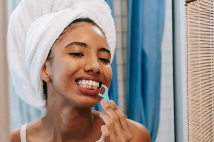 Woman flossing teeth, highlighting reasons why flossing is important.