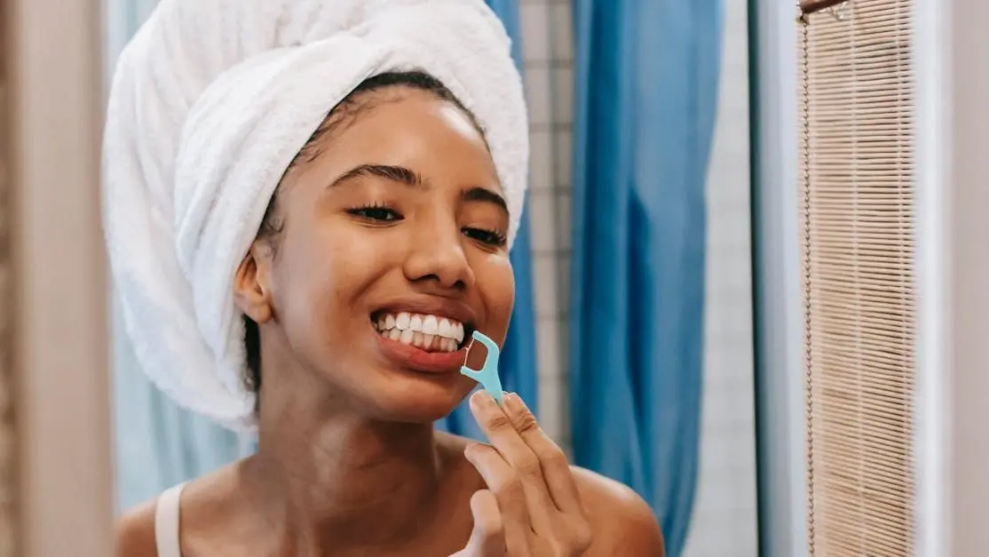 Woman flossing teeth, highlighting reasons why flossing is important.