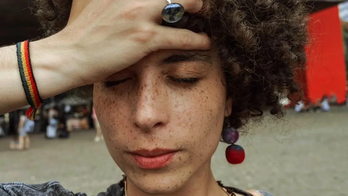 Woman holding her forehead with eyes closed, depicting techniques to reduce dental anxiety.